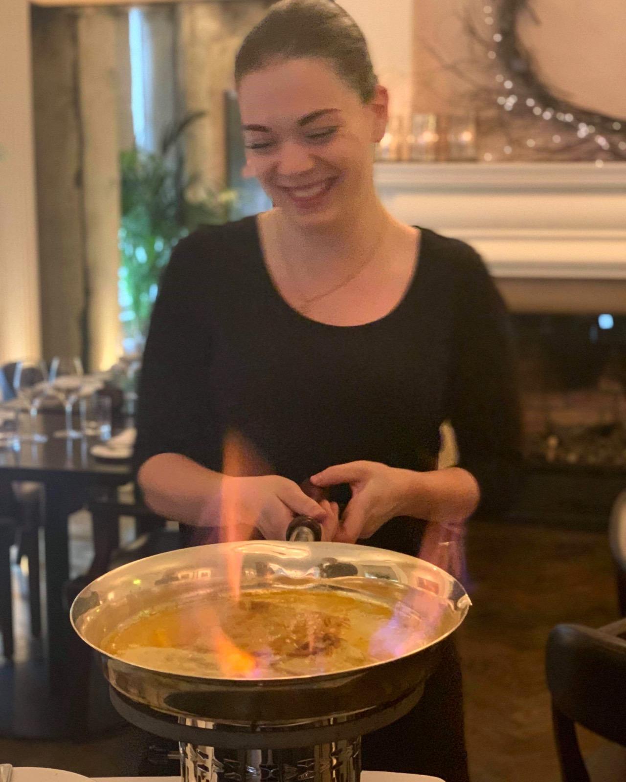 Emily flambiert ein Gericht am Tisch, praktische Arbeit im Gastgewerbe